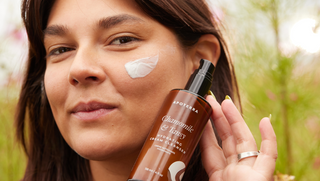 Image of woman holding bottle of Apoterra's Chamomile & Tansy Cleanser to help combat dry skin in the winter months