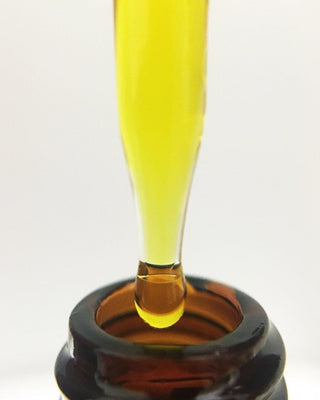 Dropper dispensing yellow liquid into bottle