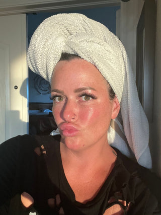 Woman with towel on head after skincare routine.