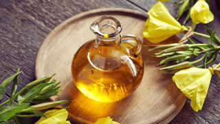 Glass bottle of oil on wooden tray with yellow flowers.