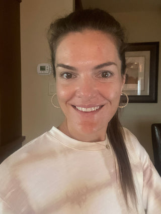 Woman smiling with hoop earrings and a tie-dye shirt