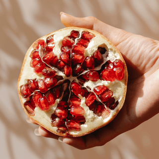 Hand holding a fresh, juicy pomegranate half