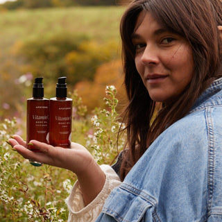 Model holding Apoterra Vitamin C Body Oil in her hand in an outdoor lifestyle photo