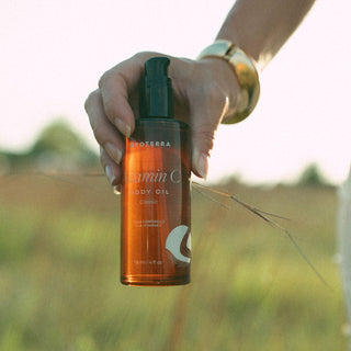 Vitamin C Body Oil by Apoterra being held outside in a meadow